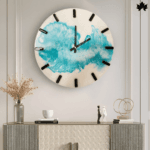 The Azure Wave - Modern Wall Clock features an artistic splash of blue resin on a clean white background, accentuated by minimalist black clock hands and bold numerals. This clock effortlessly combines functional timekeeping with contemporary wall art, making it a striking addition to any modern living space.